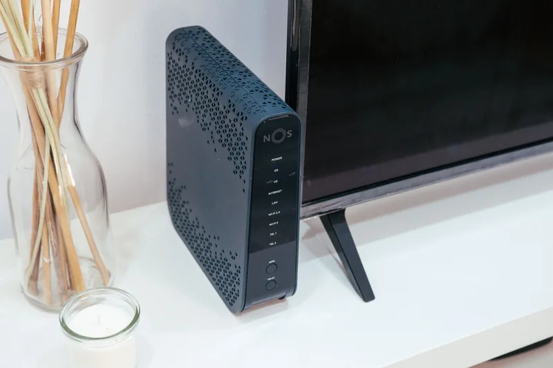 A modem and router on a shelf beneath a television