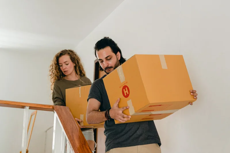 Two people carrying a box up a staircase