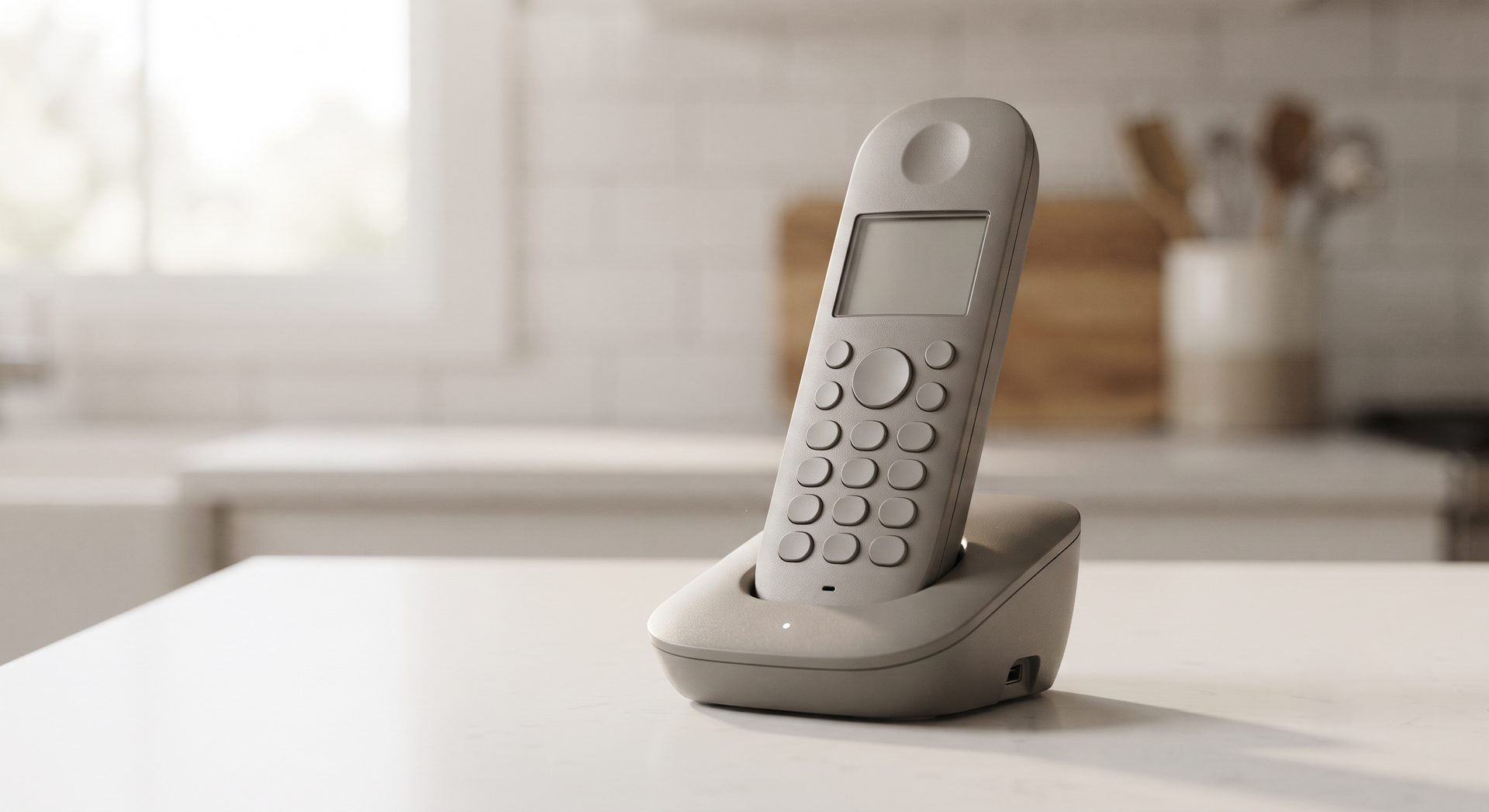 Grey cordless phone standing in its charging base on a white kitchen worktop