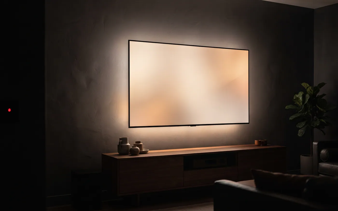 A backlit wall-mounted TV above a low wooden media console in a dark living room